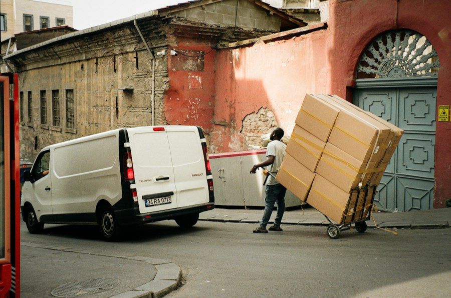 Umzugshelfer fährt Kartons auf einer Sackkarre zum Transporter